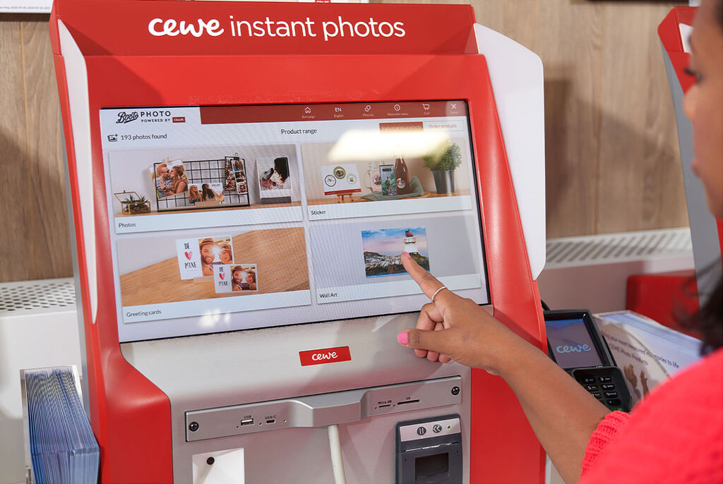 A person pointing at a CEWE Instant Photos screen with various photo products.