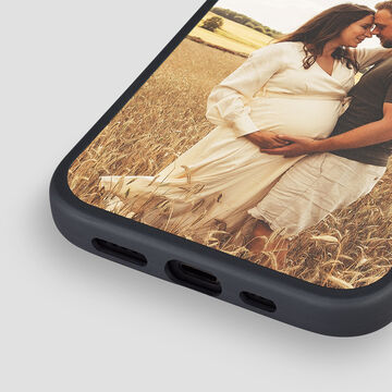 Two people smile in a field, one is pregnant.