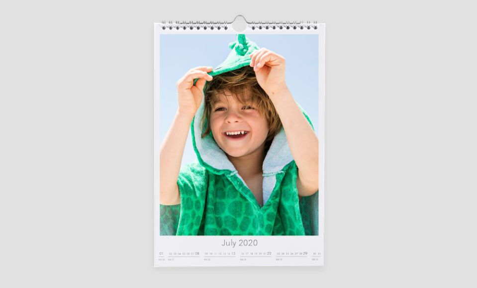 A calendar page featuring a person in a green towel posing with a handmade poncho, displaying July 2020
