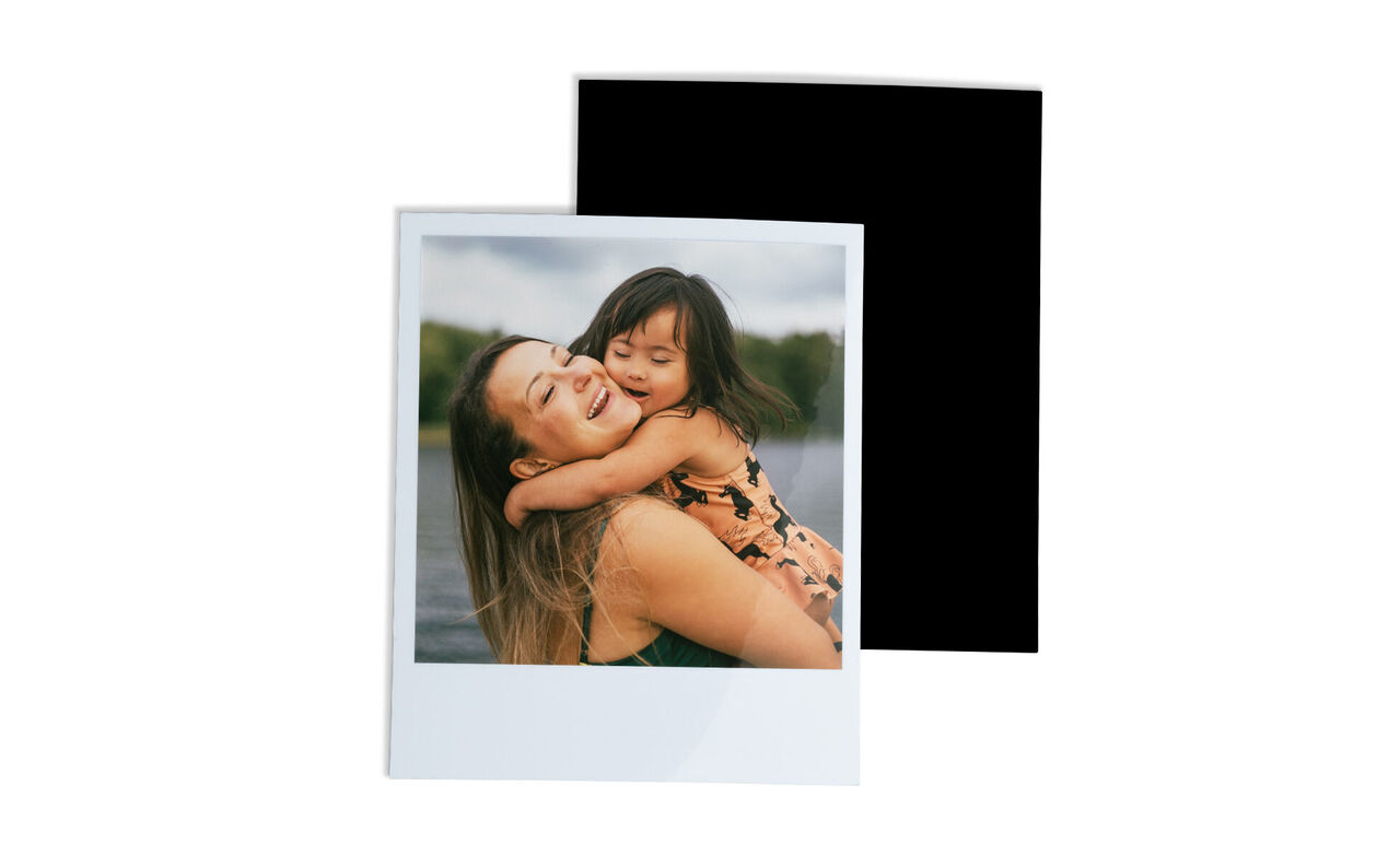 A happy mother hugging her child by the water, both laughing joyfully
