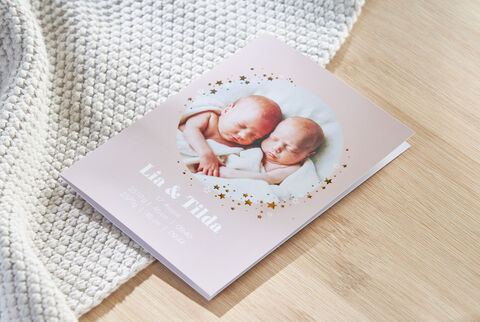 A delicate photo book with the names Lia and Tilda on the cover. It shows two sleeping twins wrapped in a soft blanket.