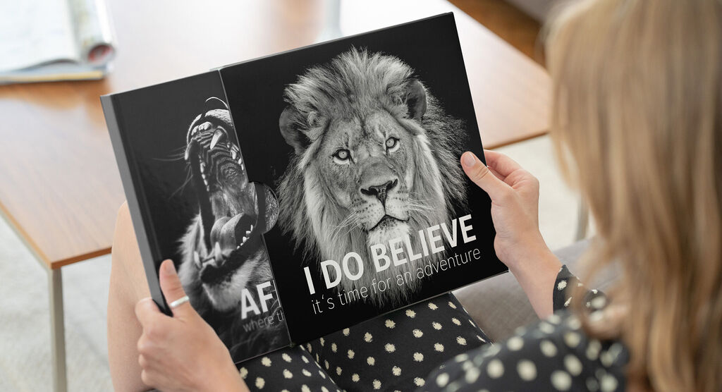 Woman reviewing a CEWE photo book with a lion on the cover.