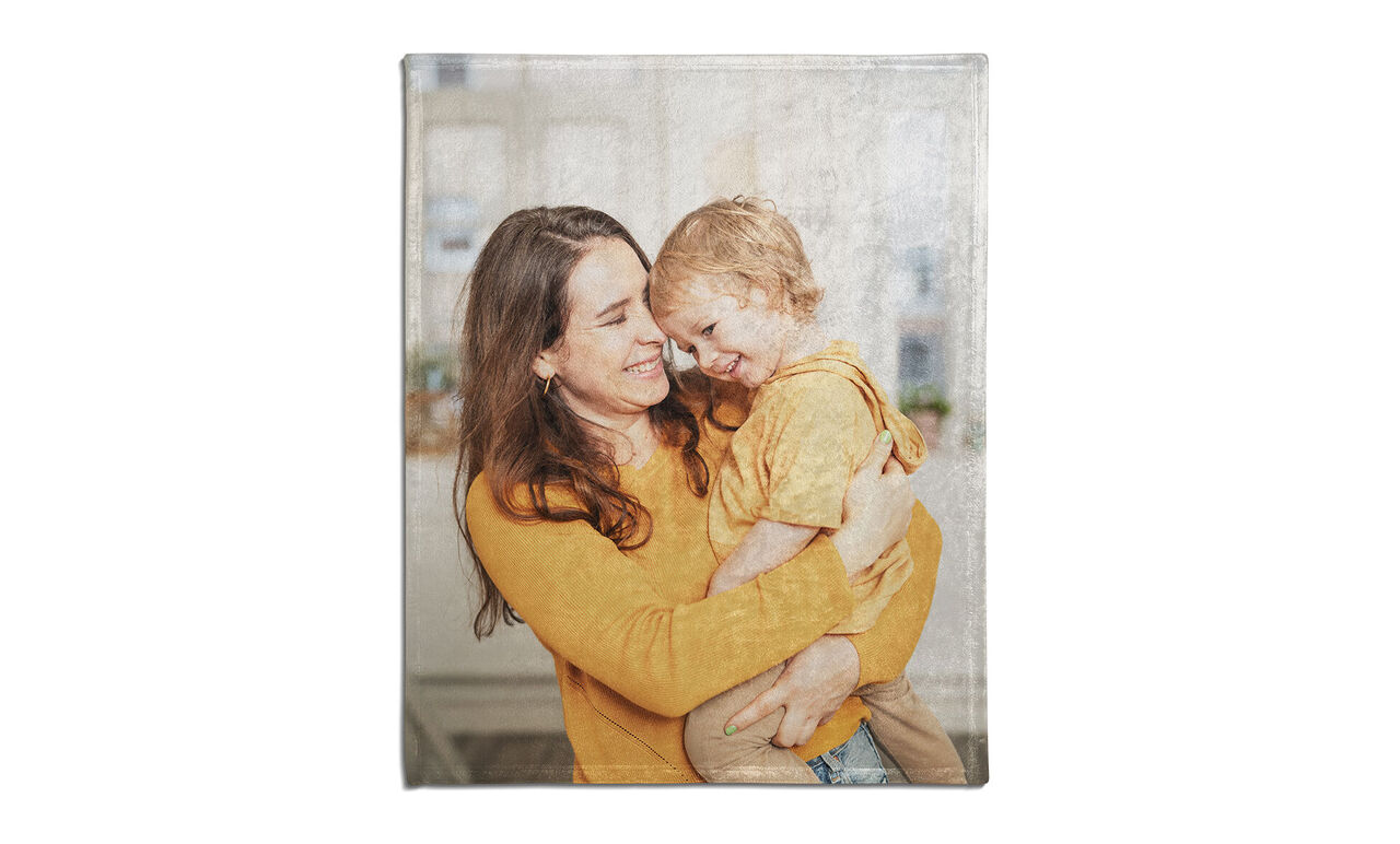 A mother hugs her child, both in warm colors