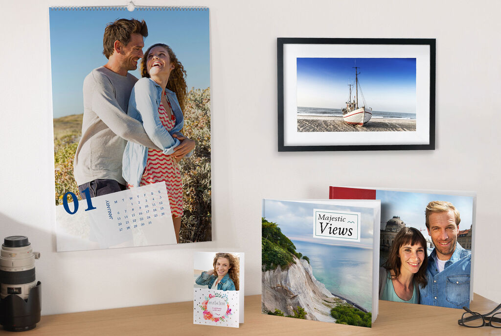 Wall picture of a beautiful landscape and boat, calendar with a couple, high-quality photo products on a table.