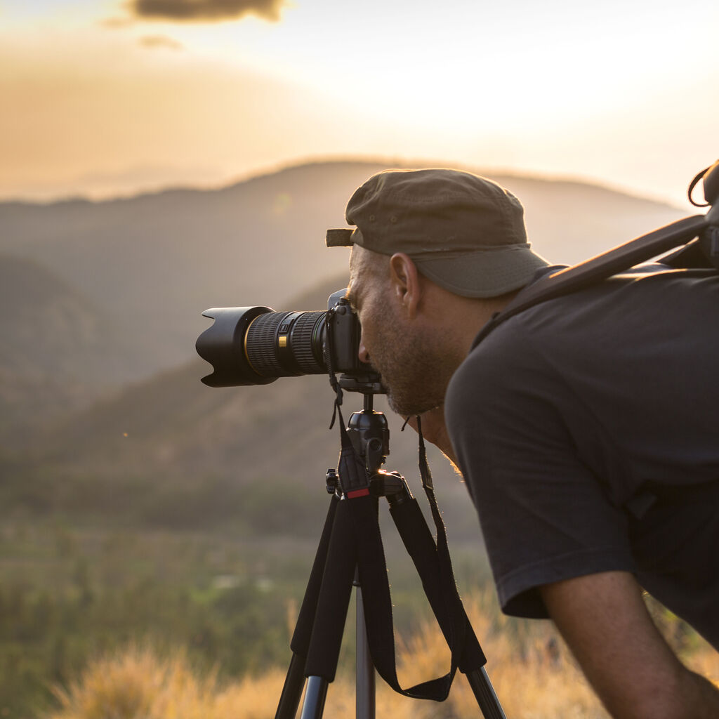 A photographer captures stunning landscapes with a camera as the sun sets.
