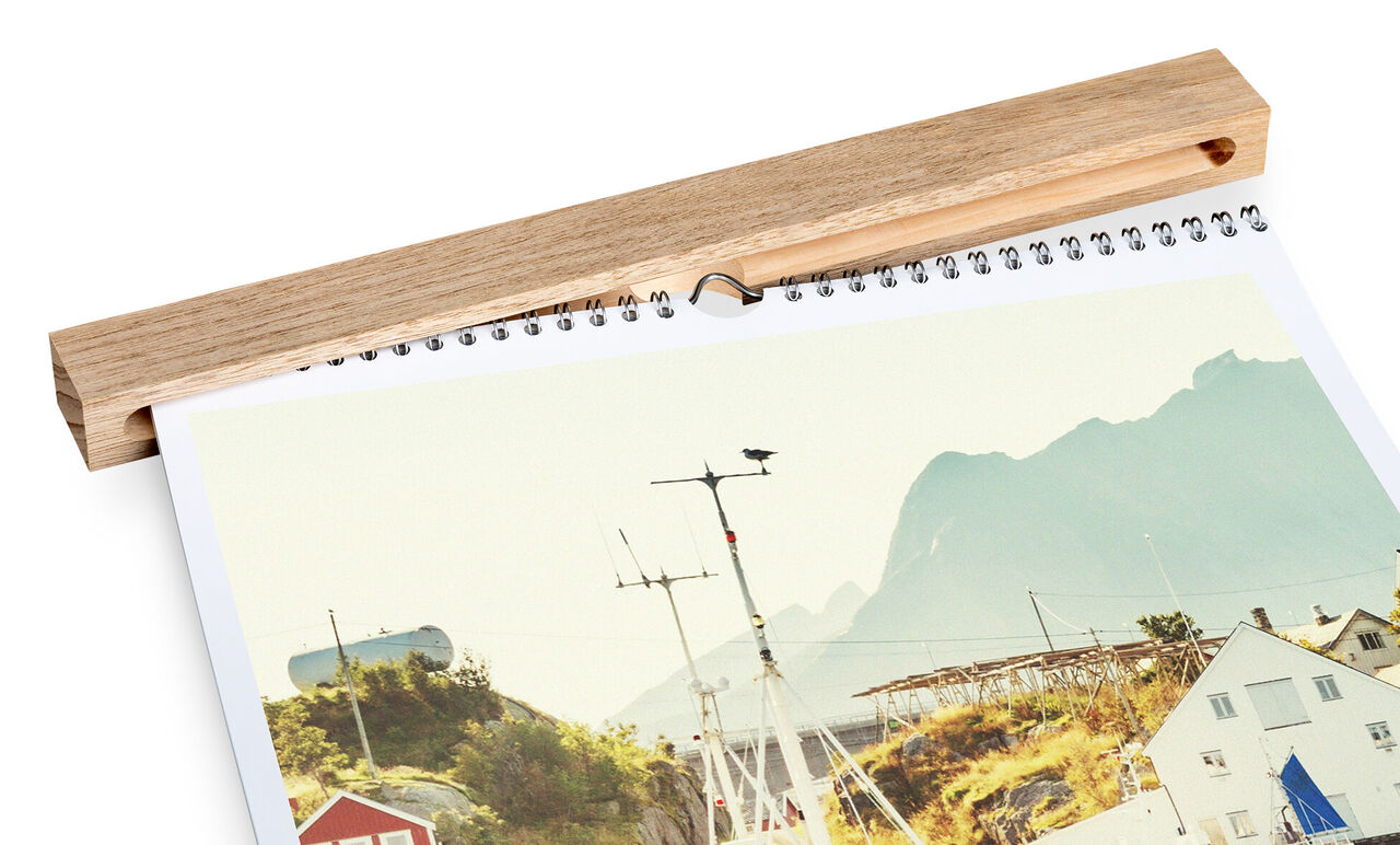 A CEWE photo calendar showcases a picturesque coastal landscape with mountains in the background.