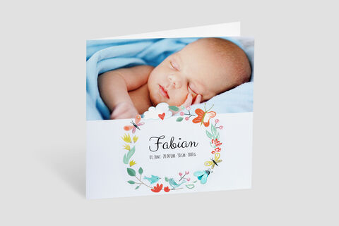 An adorable baby peacefully sleeps in a blue blanket, surrounded by colorful flowers and butterflies on the greeting card.