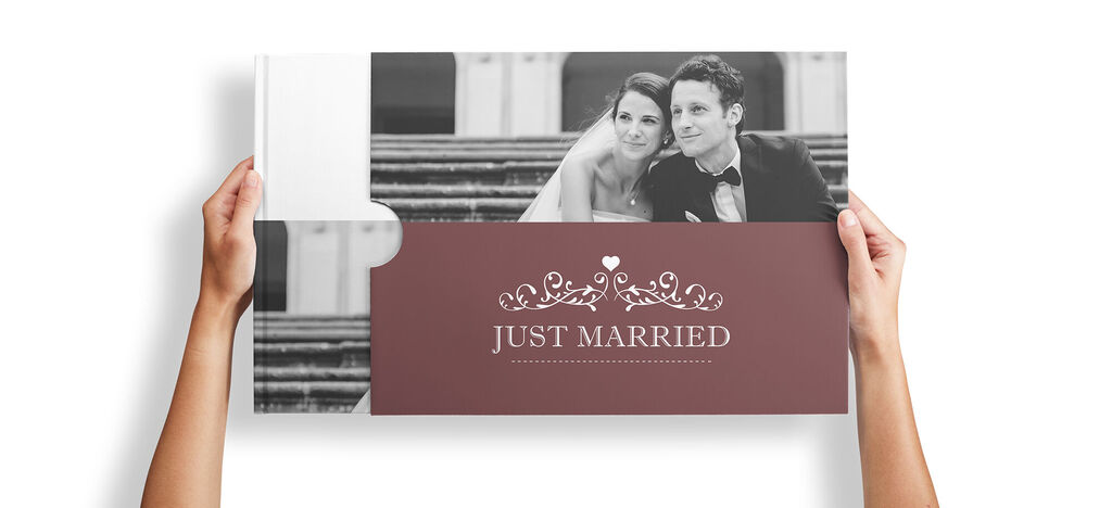 A couple holding a CEWE photo book titled Just Married.