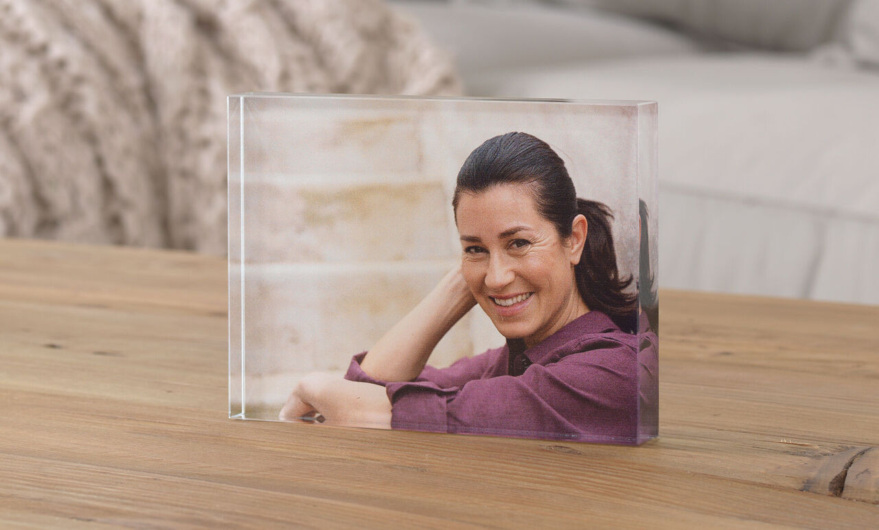 Transparent photo in a block on a wooden table, person sitting relaxed and smiling.