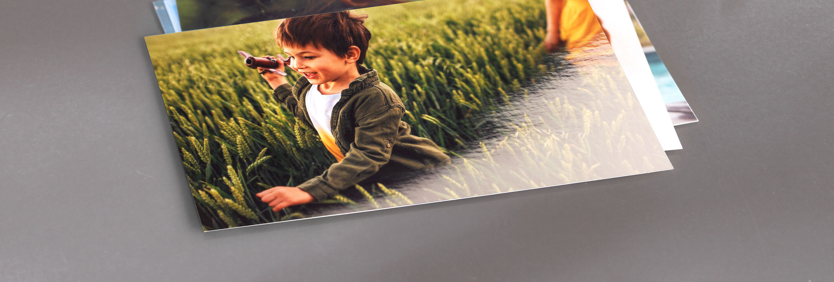A child runs joyfully through a green field holding a camera