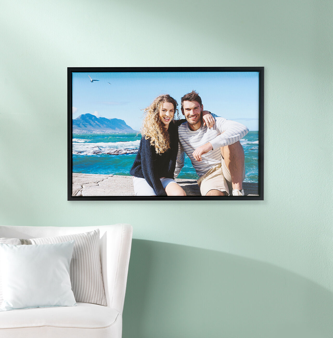 A couple poses happily in front of a beautiful coastal horizon, embracing and radiating joy from their smiles.