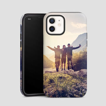 Three friends happily pose in front of a mountain landscape with a smartphone.