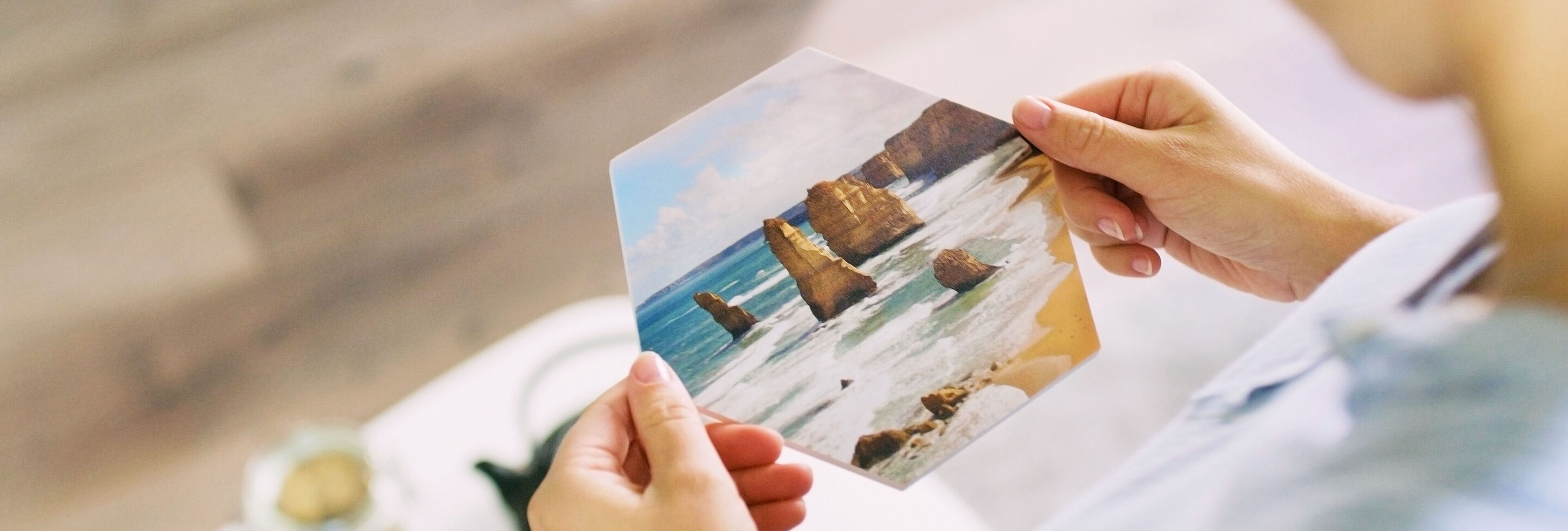 A person holds a picture of beach themes and rocks in their hands.