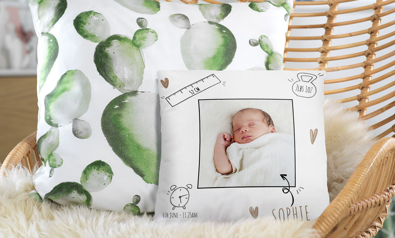 Cushion with green cactus design and another cushion with a baby photo and loving details.