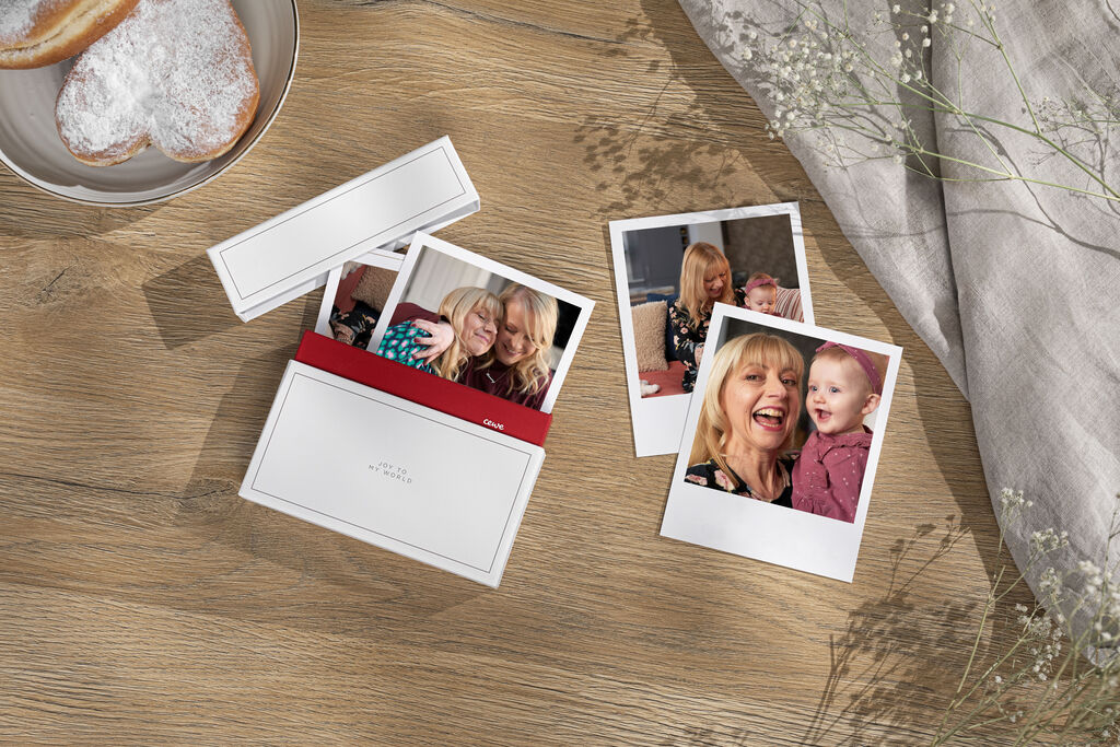 Two cheerful women on two Polaroid photos, next to a box with another photo
