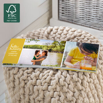 An open photo book on a cozy pouf with images from a summer day.