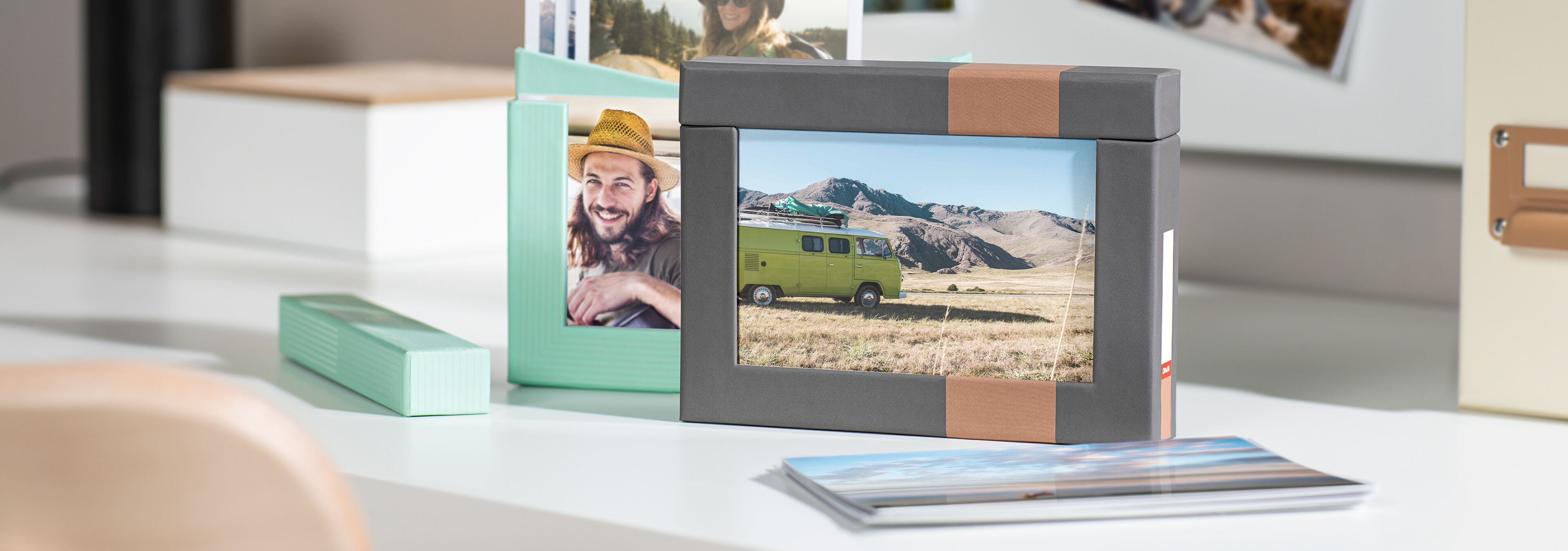 A creative arrangement of photo boxes and pictures on a table, including a gray and a mint photo box with a picture of a camping bus.