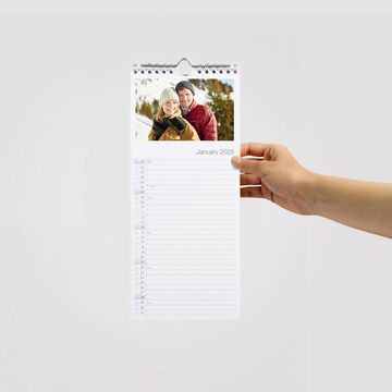 A hand holds a CEWE photo calendar featuring a happy couple on the cover.