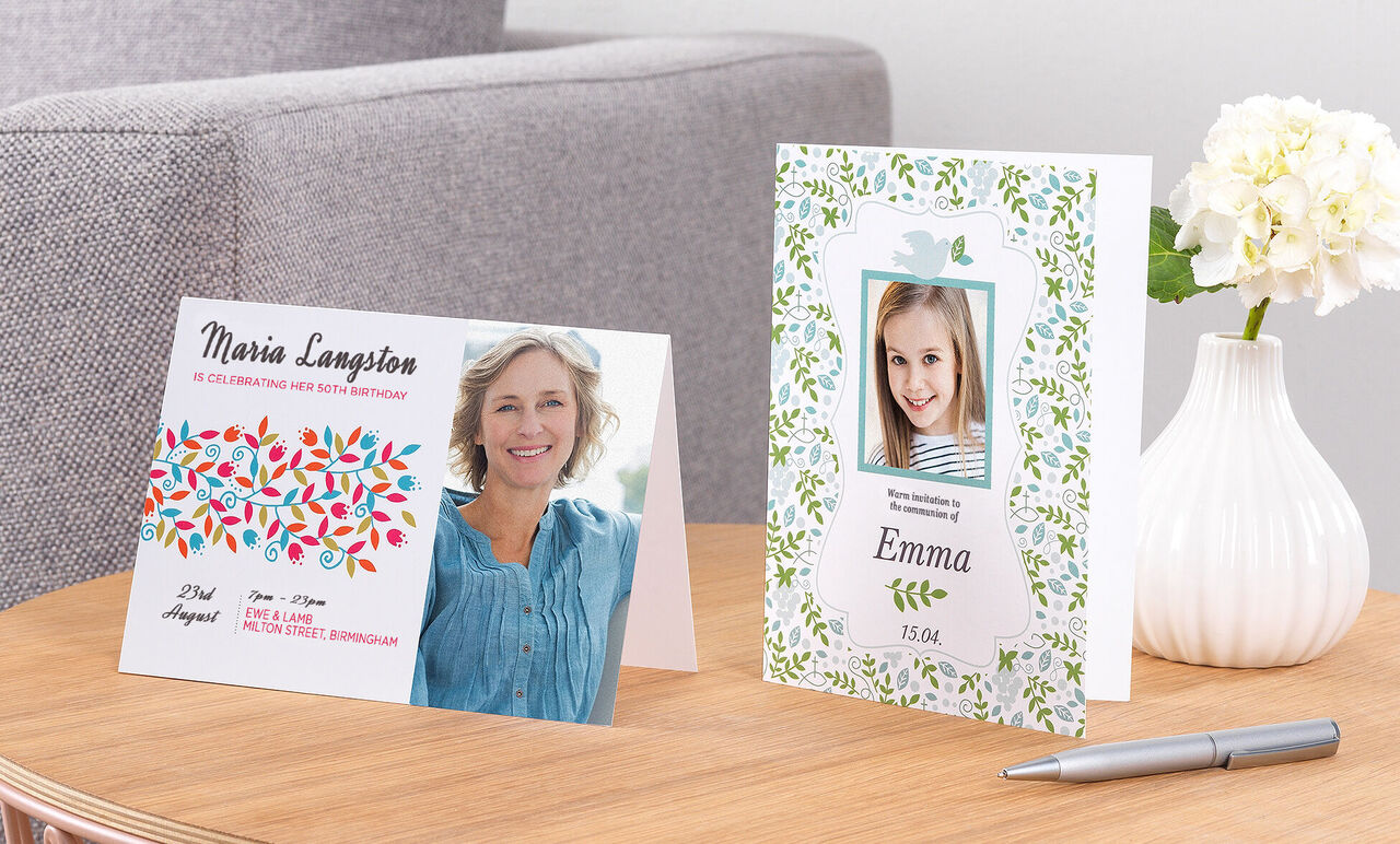 Two festive invitation cards on a table, one with colorful design and the other with floral motifs, inviting to the celebration