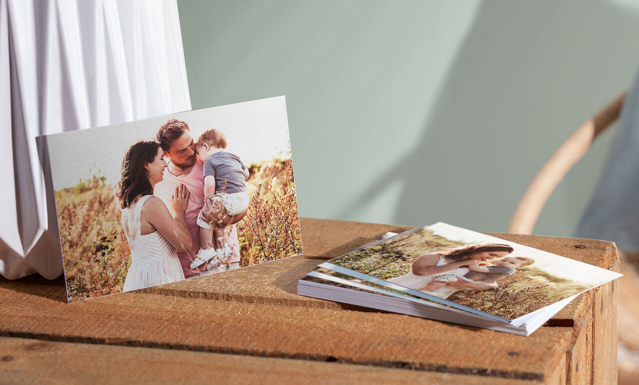 A family with a small child on a lawn shows joy. They hold a photo book and enjoy the moment.