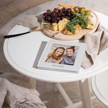 A table with snacks like grapes, cheese, and bread, along with a photo book titled "Best Friends".