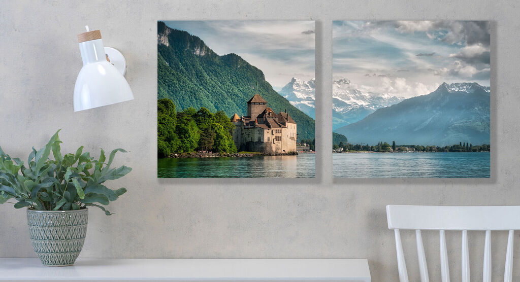 Two wall art pieces featuring mountain scenery and a castle in the background, bright sky.