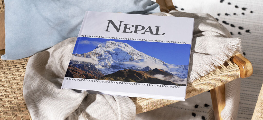 CEWE photo book titled 'Nepal' on a wooden chair with a blanket
