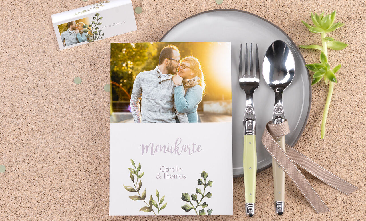 A beautifully set table with a menu card showing names and a floral design