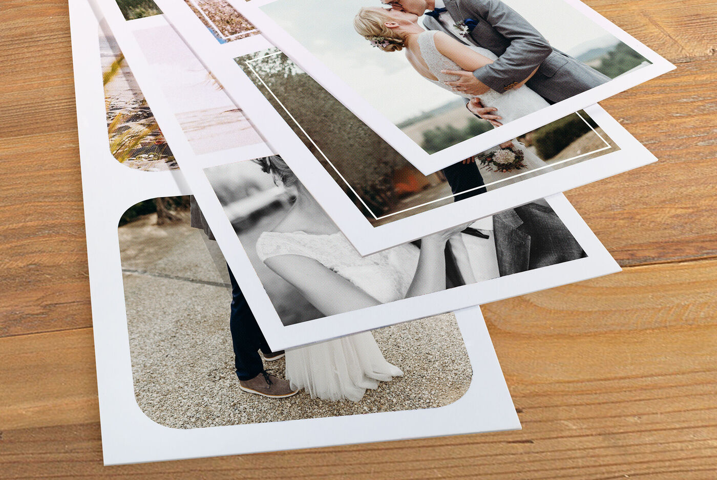 Various photos lay stacked on a wooden table.