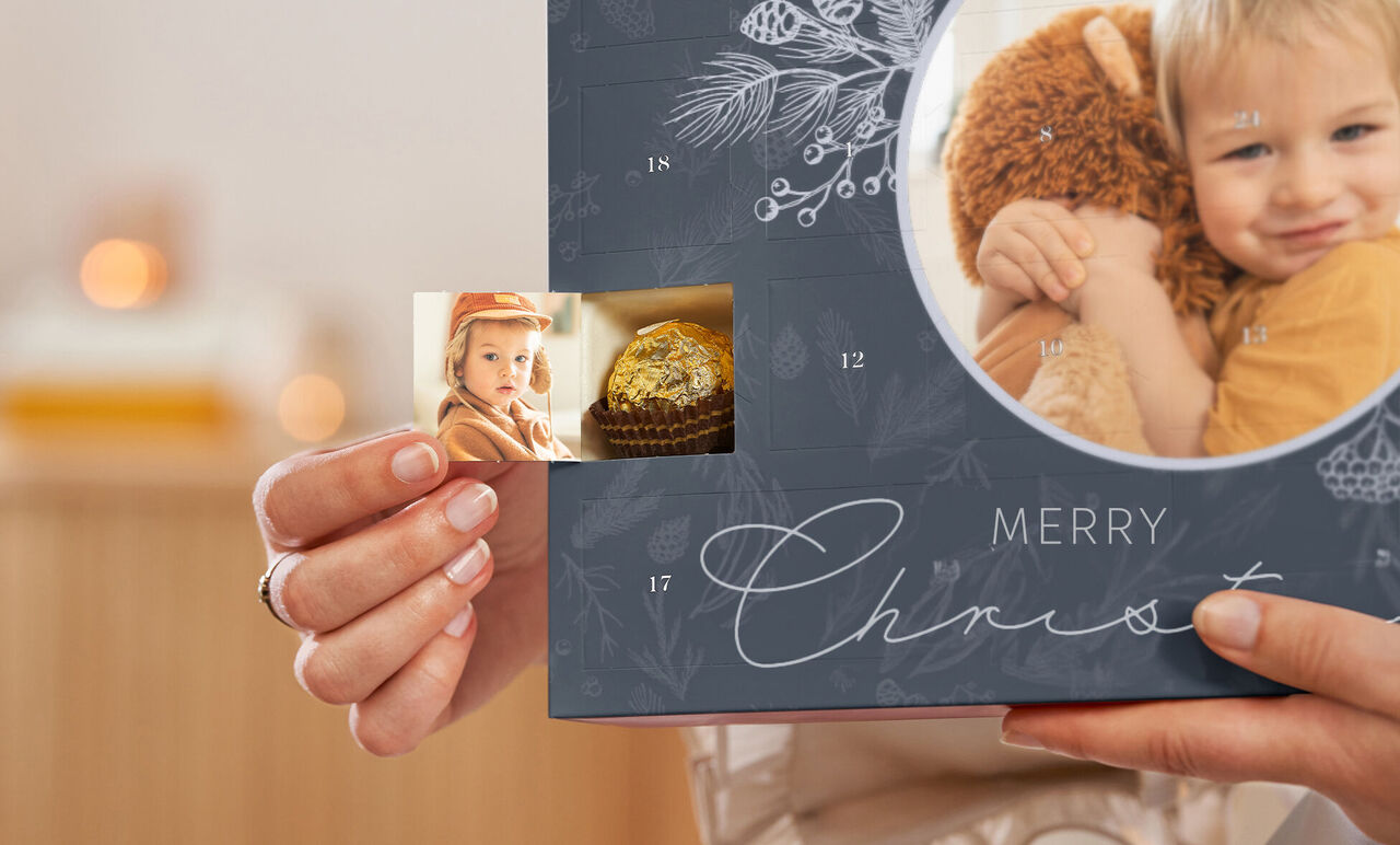 A person holds a Christmas photo book featuring a personal photo and festive layout.