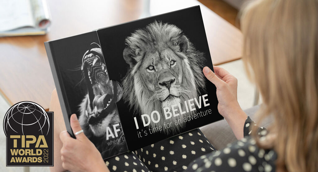 Two pages of a photo book show a lion and a warrior with text "I DO BELIEVE".