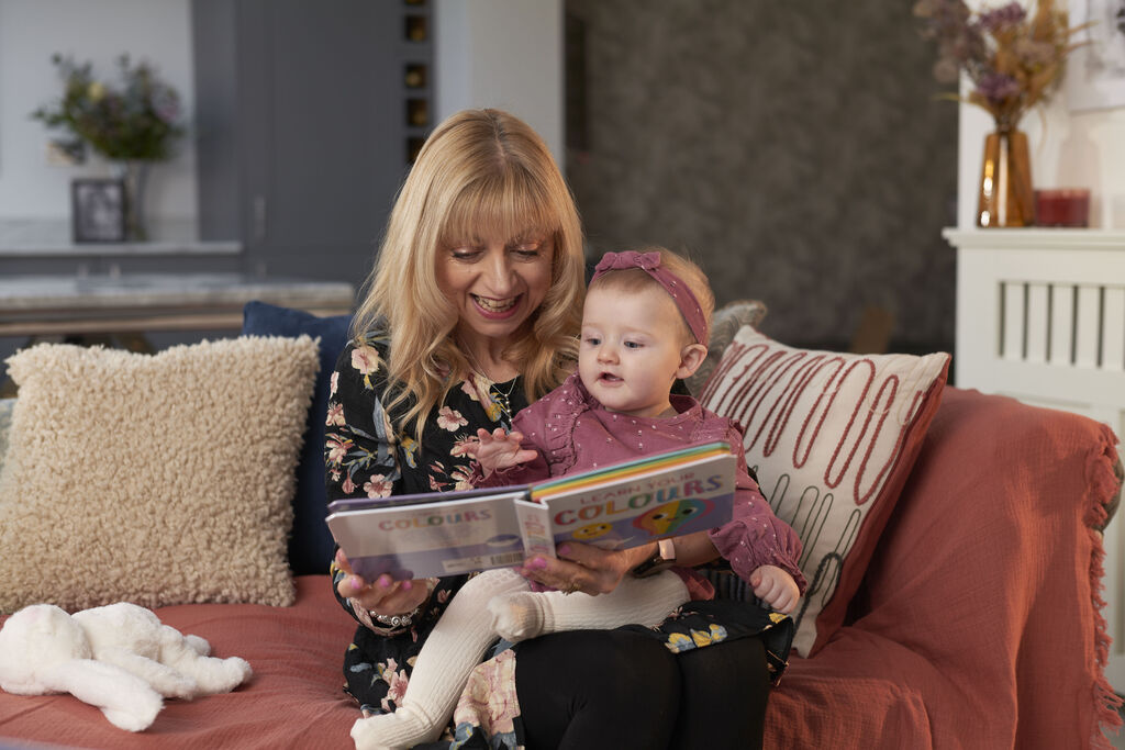A loving scene where a mother and her child look at a picture book together and enjoy it
