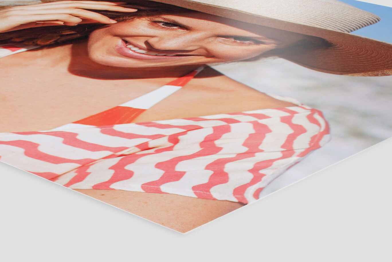 A cheerful woman in a straw hat smiles at the camera while wearing a summer outfit