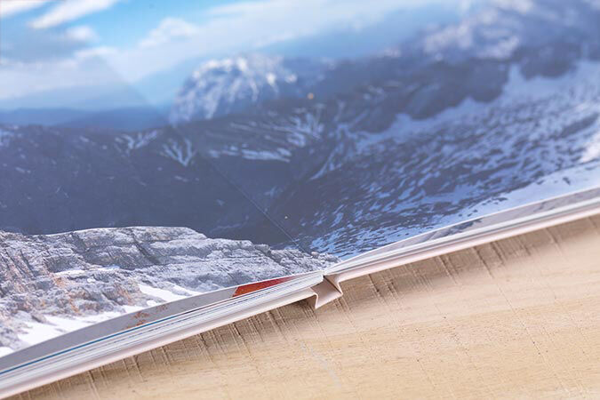 An open page of a photo book with a mountain landscape in the background.