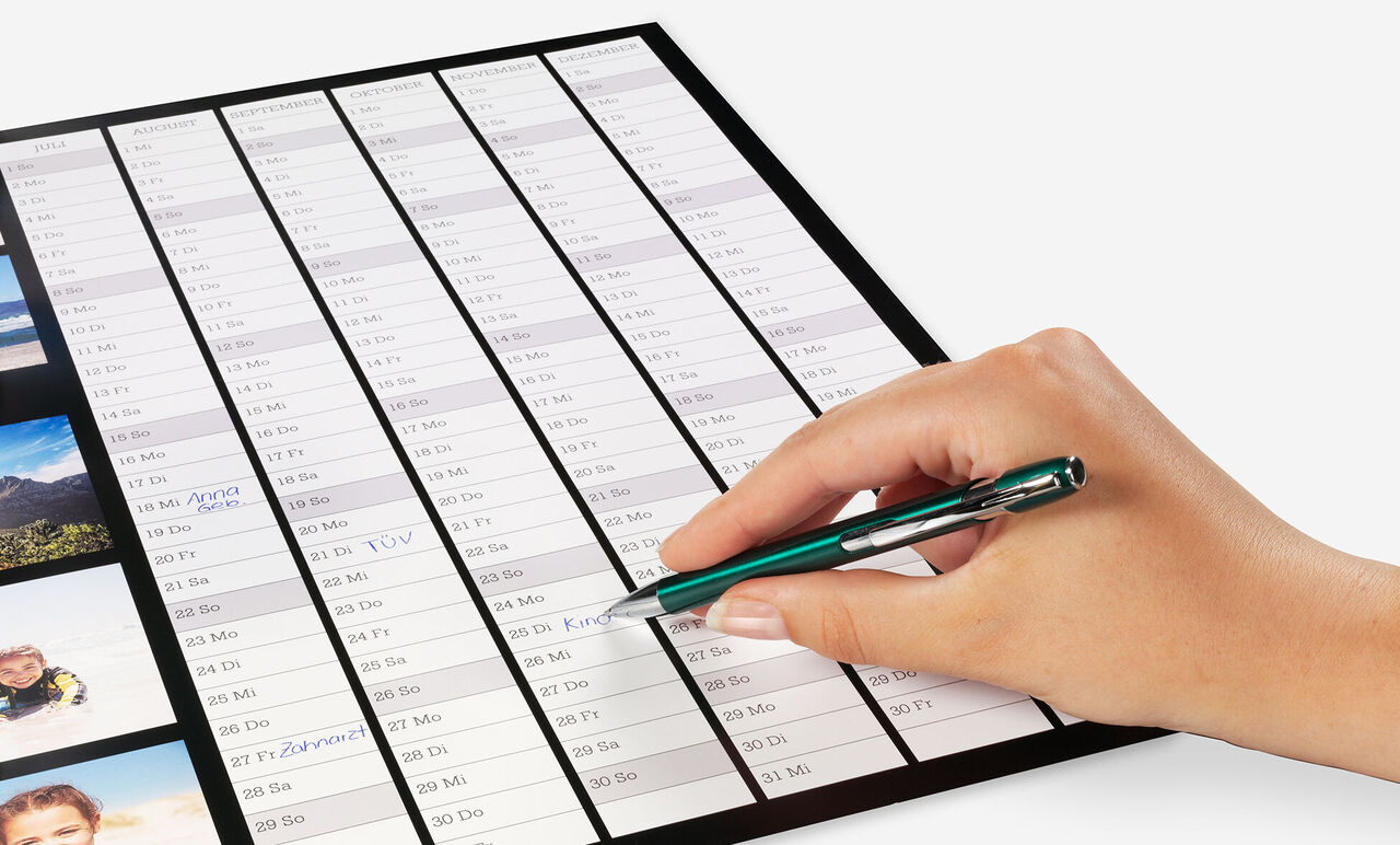 Hand writing on a calendar with a pen showing a planning element