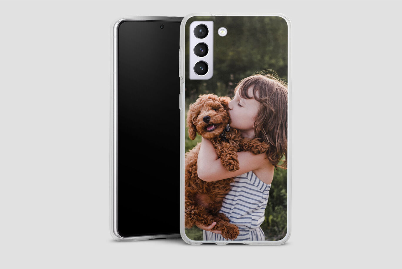 Girl holds a happy dog in her arms with a smartphone in the background.