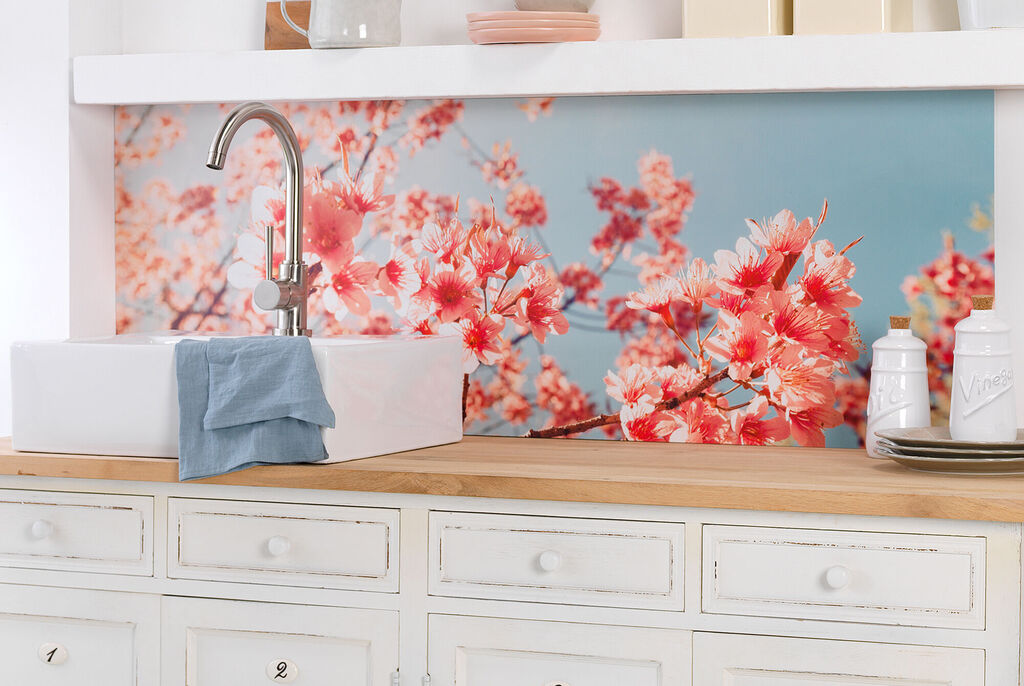 Bright kitchen with a sink and wall decoration of cherry blossoms in soft pink tones.