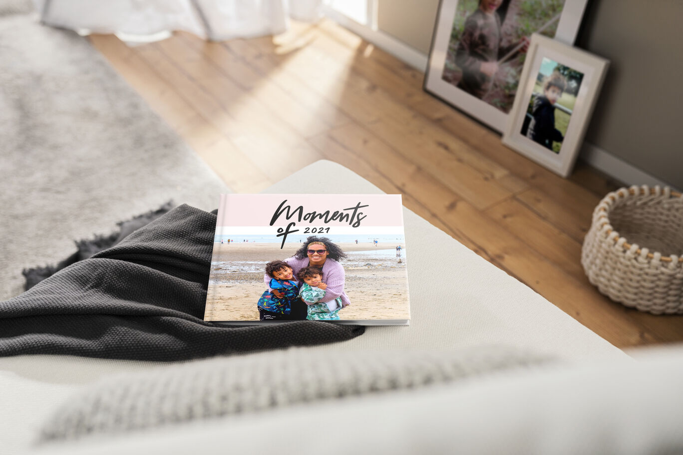 A CEWE photo book with the inscription 'Moments of 2021' on a cozy couch in the living room.