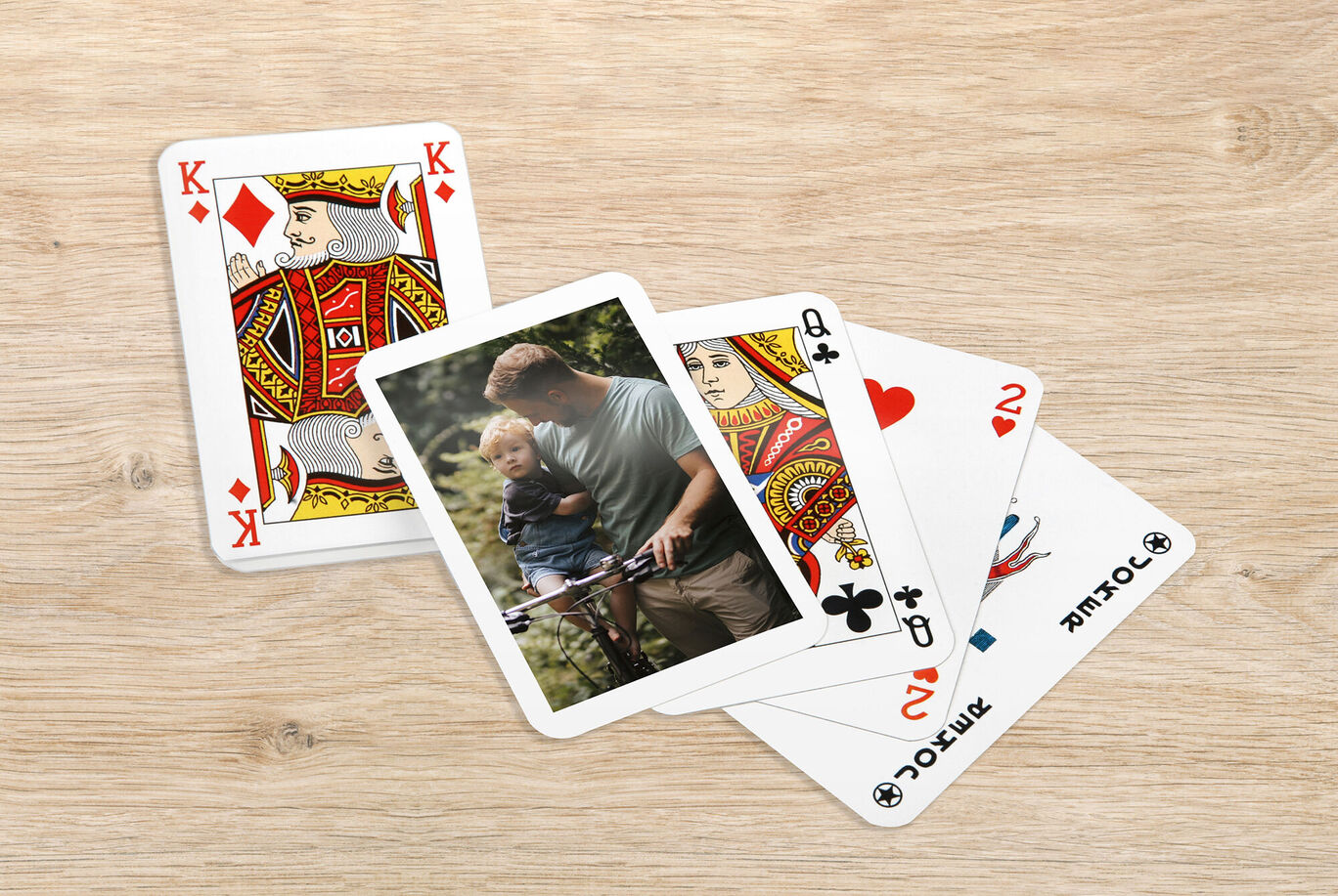Family playing with playing cards on a light wooden table.