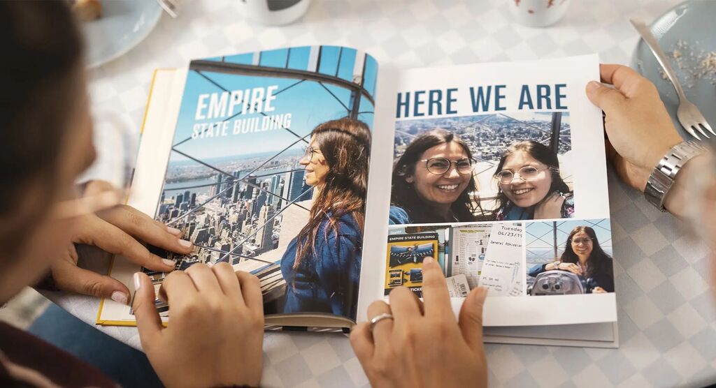 Two people are flipping through a photo book with memories and images of a view.