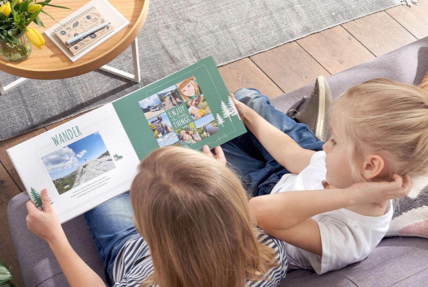 Two children are flipping through a CEWE photo book about hiking adventures.