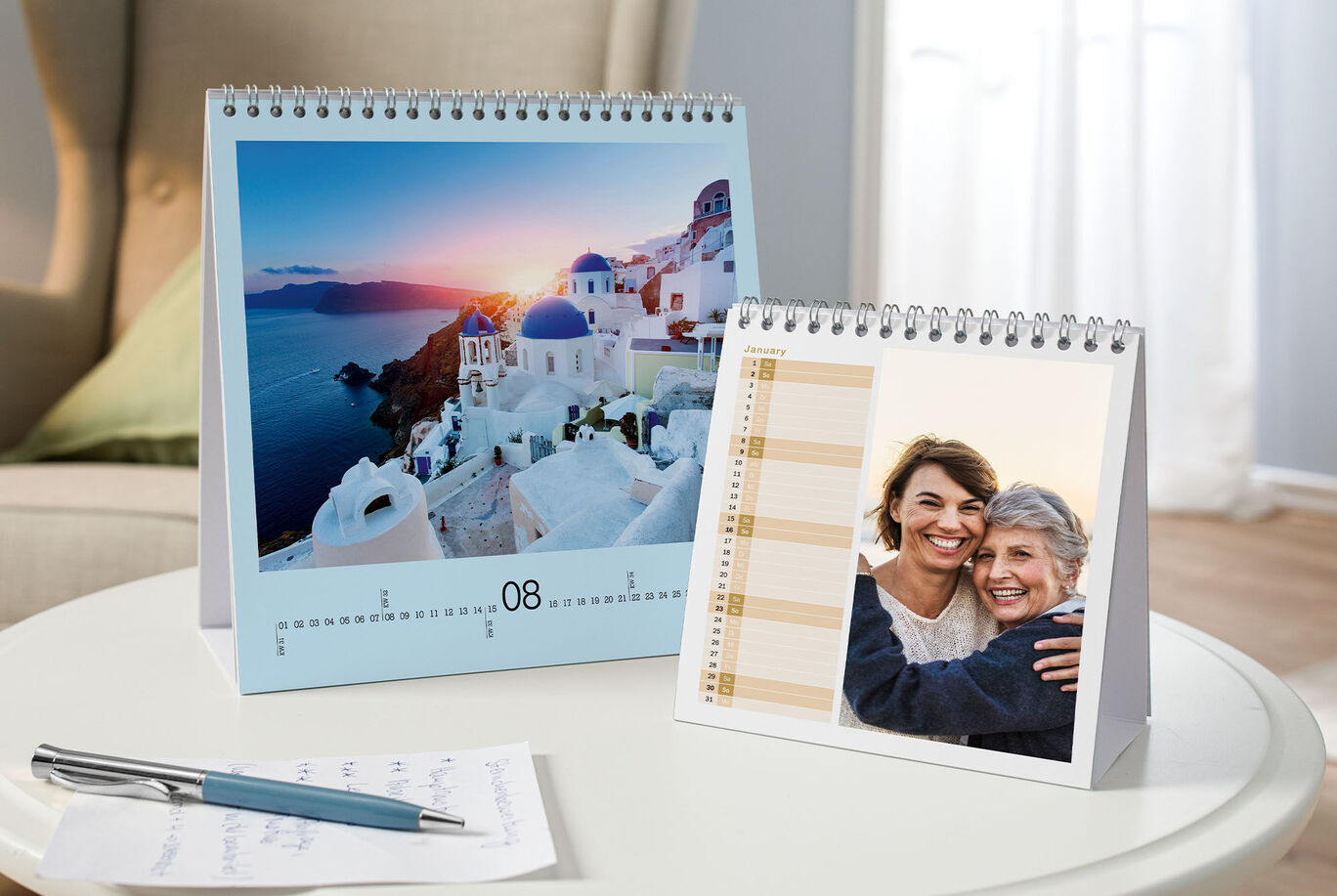 Two desk calendars with dreamlike vacation motifs, one shows the beautiful landscape of Santorini, the other a heartwarming photo of two people