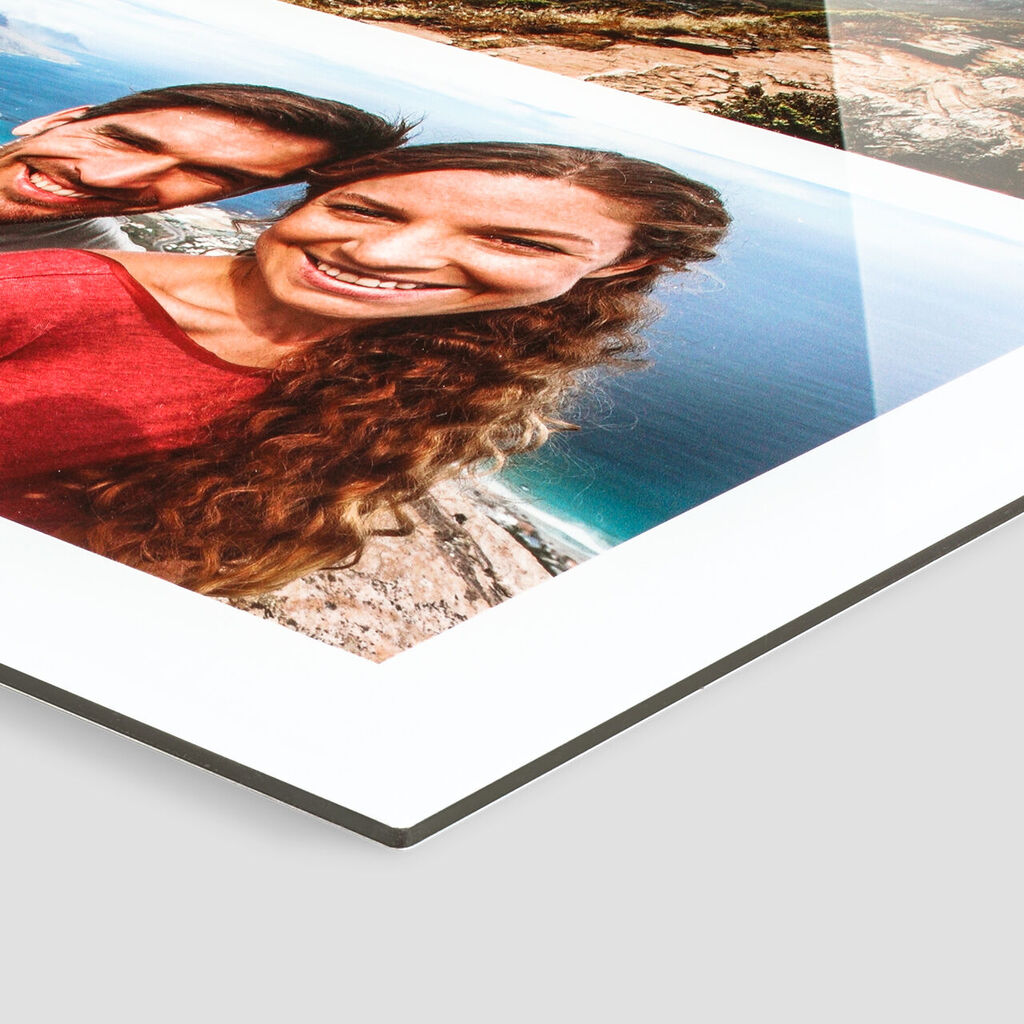 A happy couple smiles at the camera, the ocean sparkling in the background. CEWE photo book.