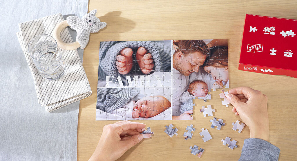Great snapshot of a puzzle with family photos and a personified baby toy figure on a table.