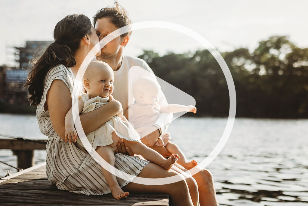 A happy family sits by the water and enjoys their time together.