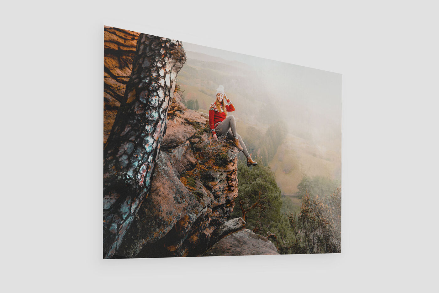 A woman sits on a rock in nature enjoying the view