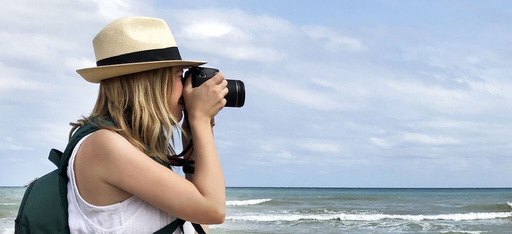 Woman with a camera taking a photo at the beach