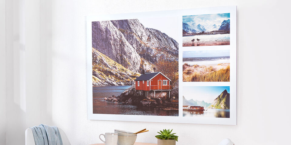 A wall picture with stunning landscape shots in a modern frame. It shows a red house by the water, surrounded by mountains and more impressions of nature.