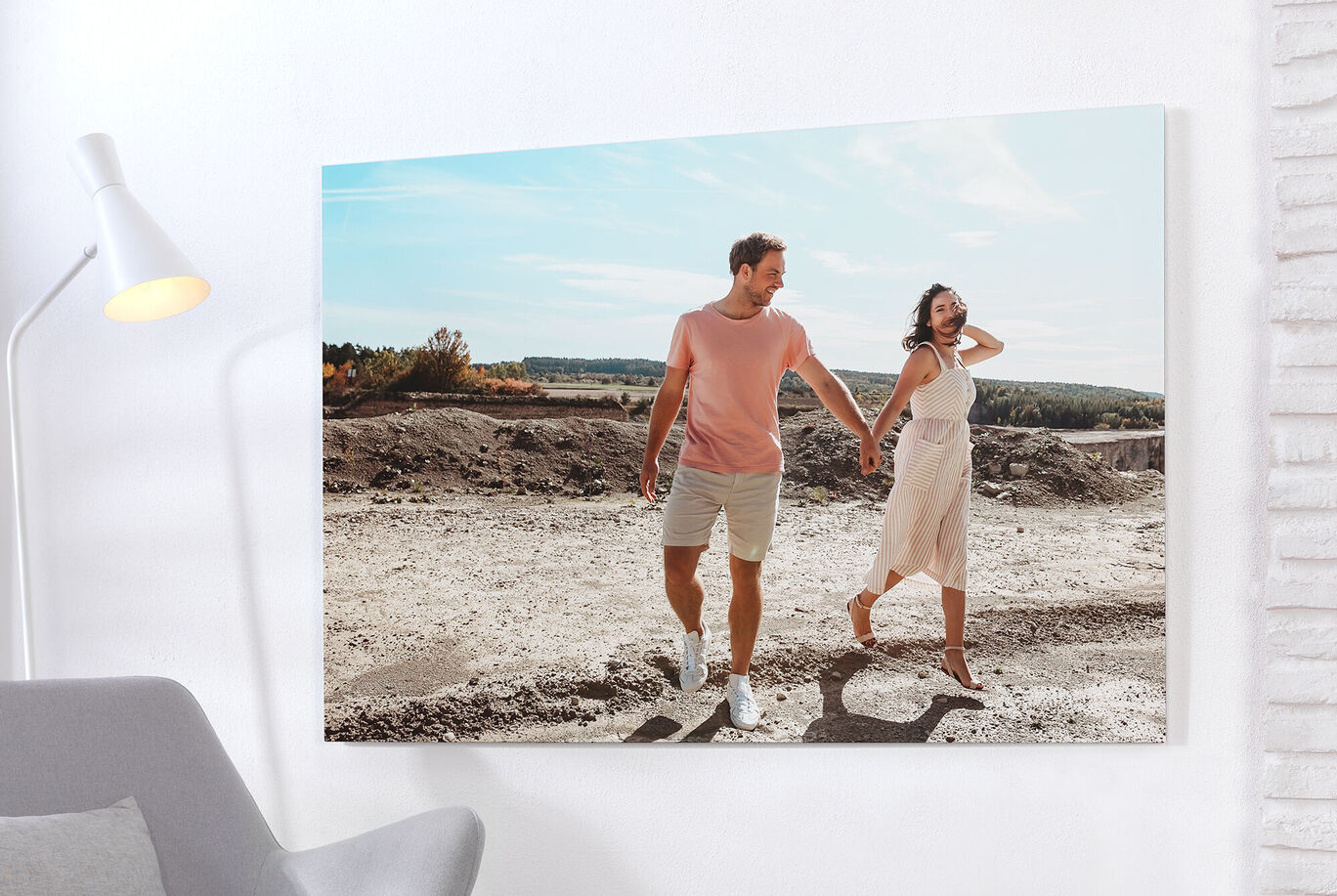 A couple holds hands and walks along a sandy path. They radiate joy.