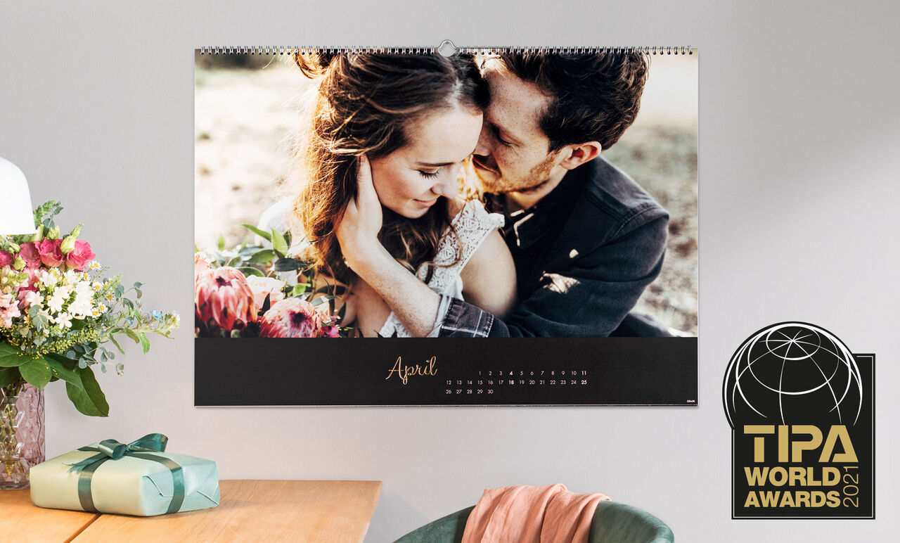 A romantic calendar featuring a snapshot of a couple embracing, decorated with colorful flowers and a gift.